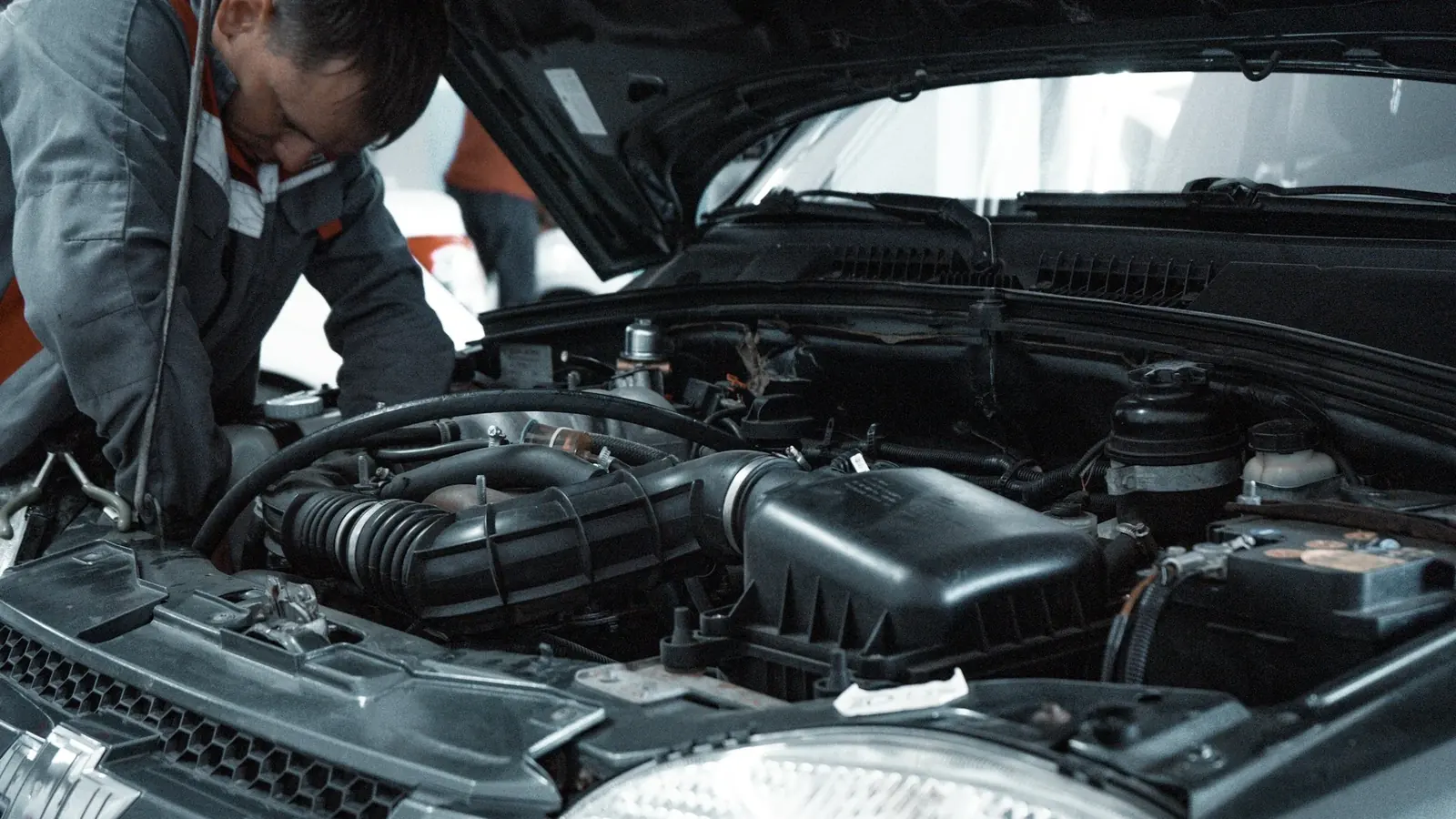 Kaputu açık aracın motorunu inceleyen teknisyen