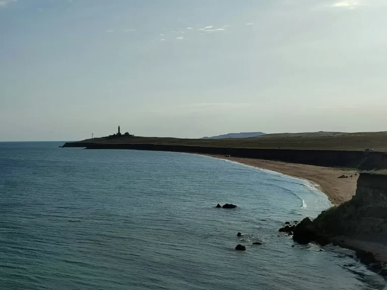 Kıyı şeridinde deniz feneri ve kumsal